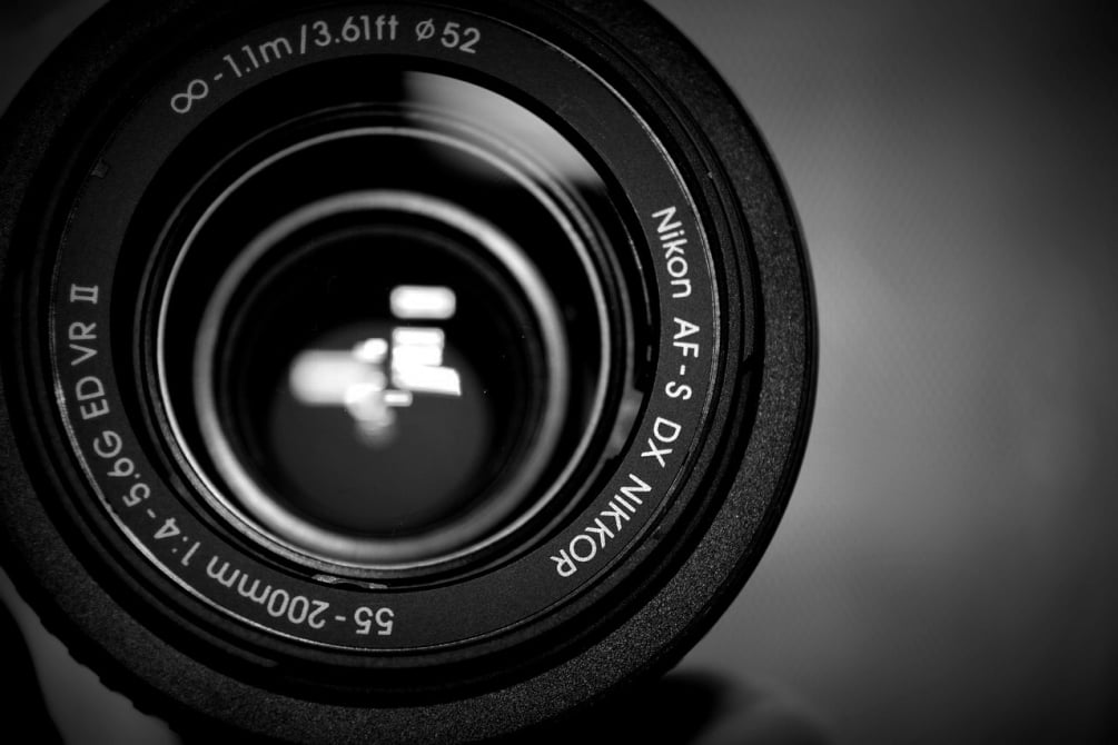 Extreme close-up of a black Nikon AF-S DX Nikkor camera lens showing technical specifications and glass lens reflections